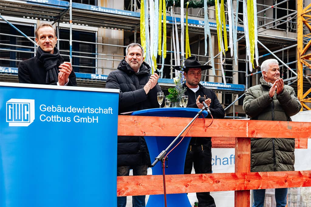 Abgebildet sind Dr. Sebastian Herke, Oberbürgermeister Tobias Schick, Zimmermann Toni Hannusch (Böhm Bedachungen) und Jörg Schnapke (Geschäftsführer Sternbau GmbH).